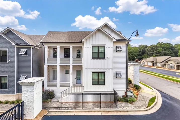 Contemporary white siding exterior with dark-framed windows, a covered front porch, and a second-story balcony