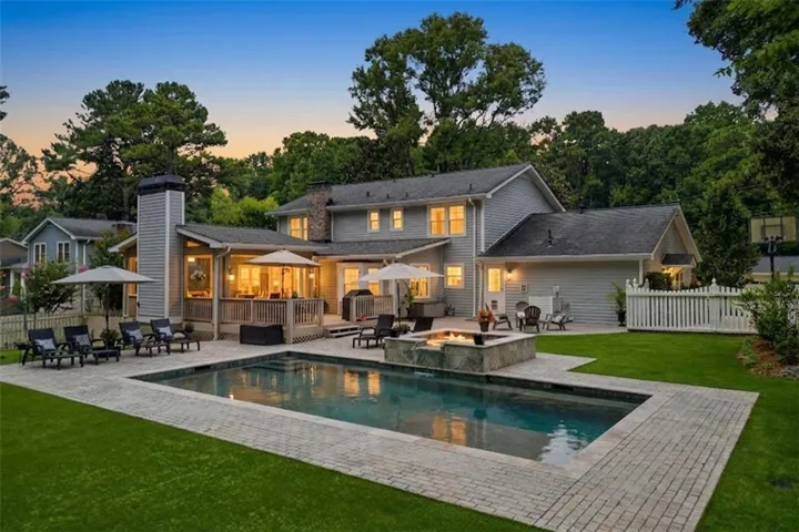 Expansive paver patio surrounding an in-ground swimming pool and integrated fire pit
