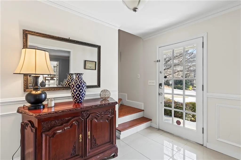 Doorway featuring light tile patterned floors, stairs, a wealth of natural light, and crown molding