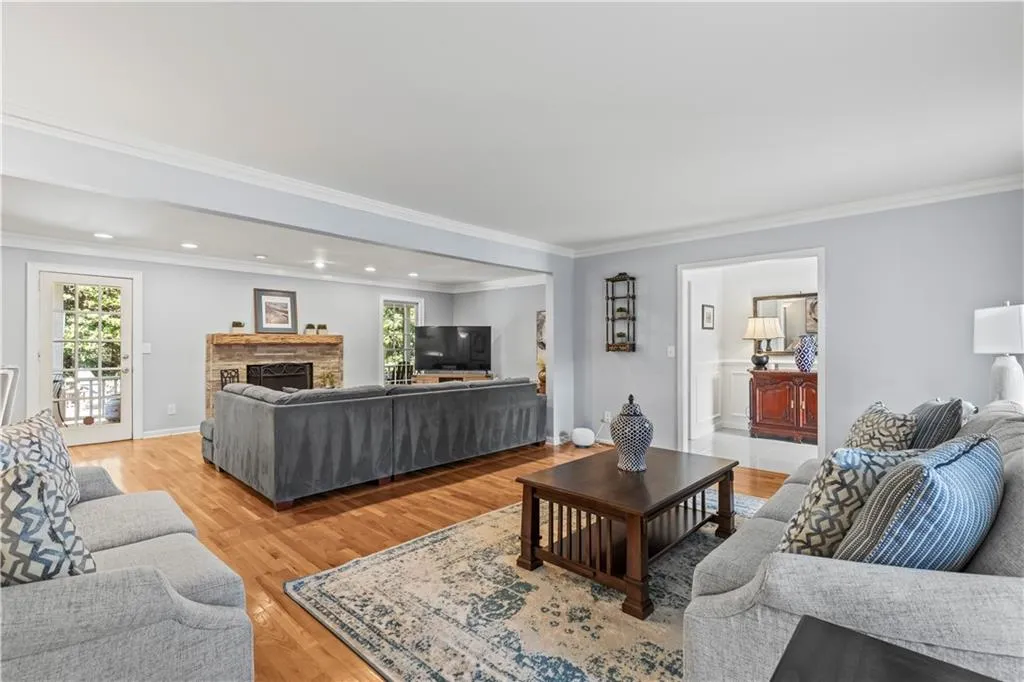 Living area with recessed lighting, light wood-type flooring, a fireplace, and crown molding