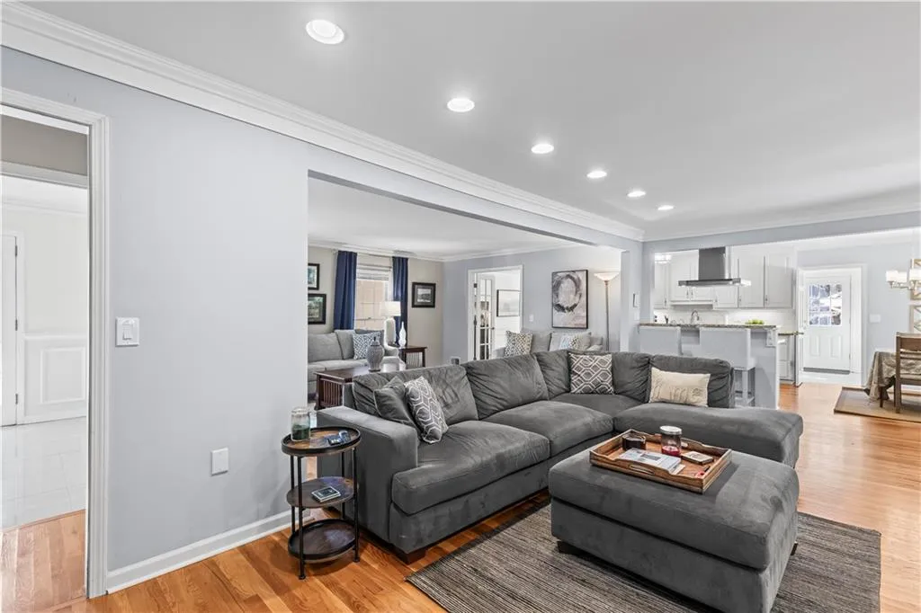 Living area featuring crown molding, recessed lighting, an inviting chandelier, light wood-style floors, and baseboards
