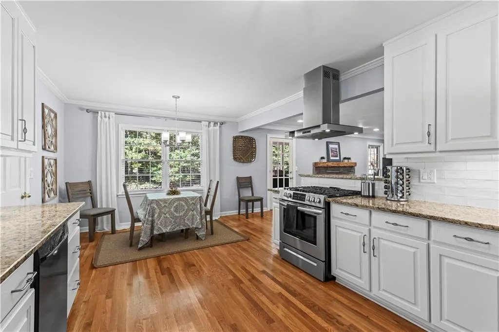 Kitchen featuring black dishwasher, decorative backsplash, stainless steel gas range, island exhaust hood, and crown molding