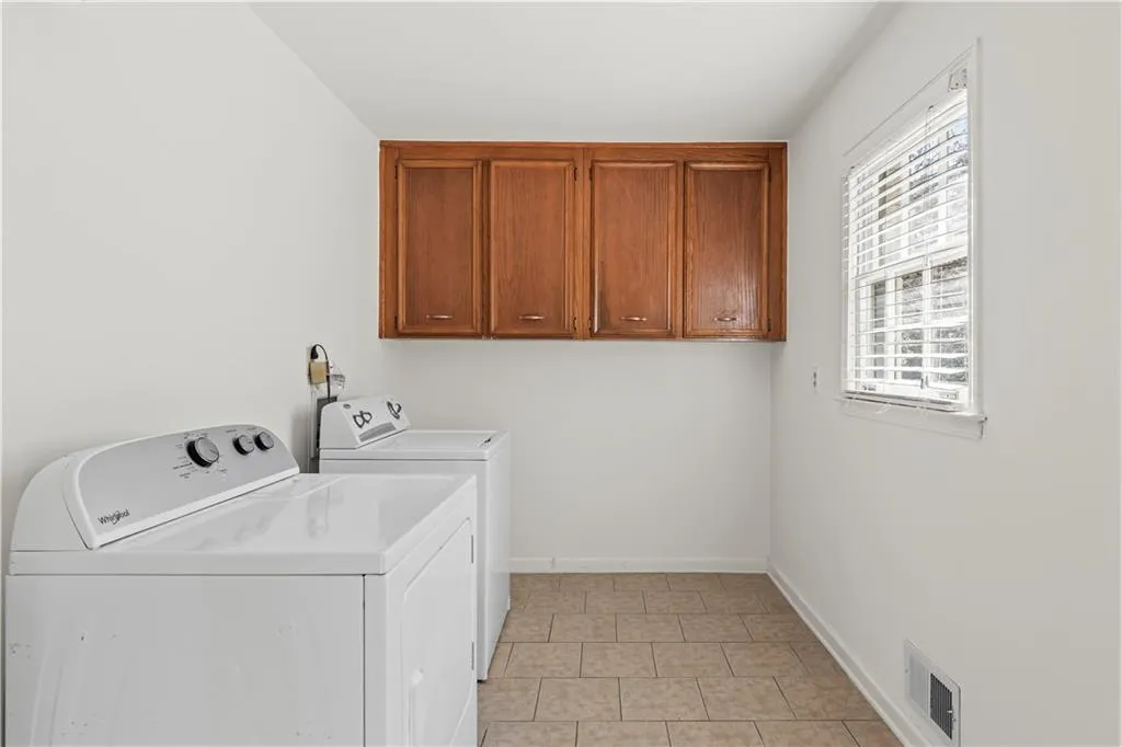 Laundry room featuring cabinet space, light tile patterned floors, baseboards, visible vents, and washing machine and clothes dryer