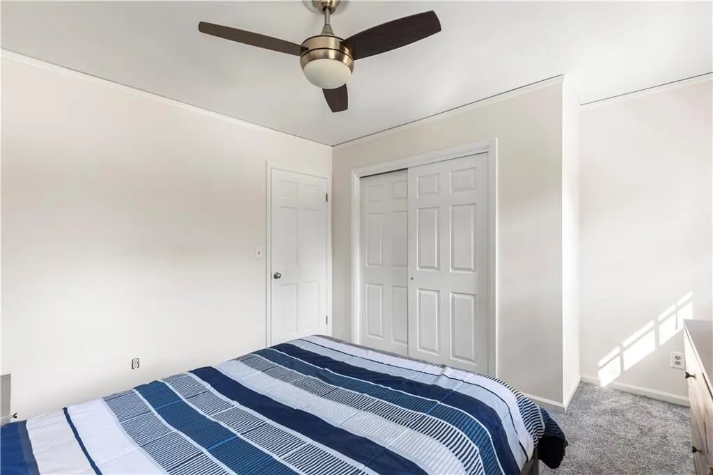 Bedroom with a closet, carpet flooring, a ceiling fan, and baseboards