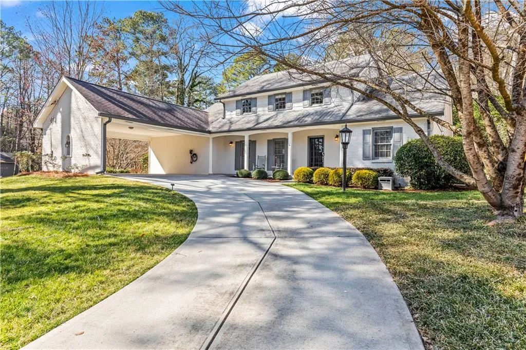 View of front facade with a front yard, concrete driveway, brick siding, and covered porch