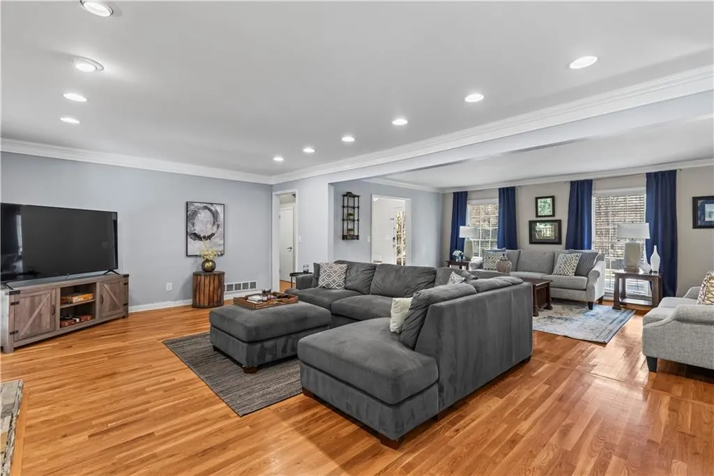 Living room featuring light wood-style flooring, visible vents, ornamental molding, and baseboards