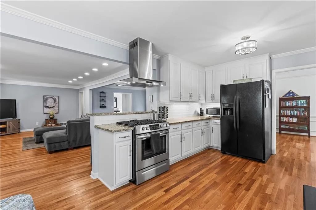 Kitchen with stainless steel appliances, extractor fan, a peninsula, and crown molding