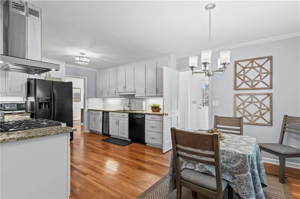 Kitchen featuring crown molding, an inviting chandelier, beverage cooler, black appliances, and extractor fan