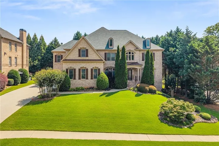 Stately brick-front residence featuring a gabled roof, dormer windows, and a covered portico entrance supported by columns