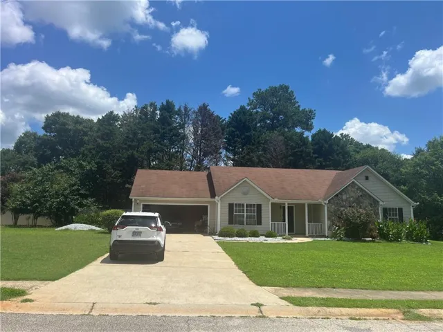 Single-story residence featuring a two-car garage, stone accent siding, and a covered front porch