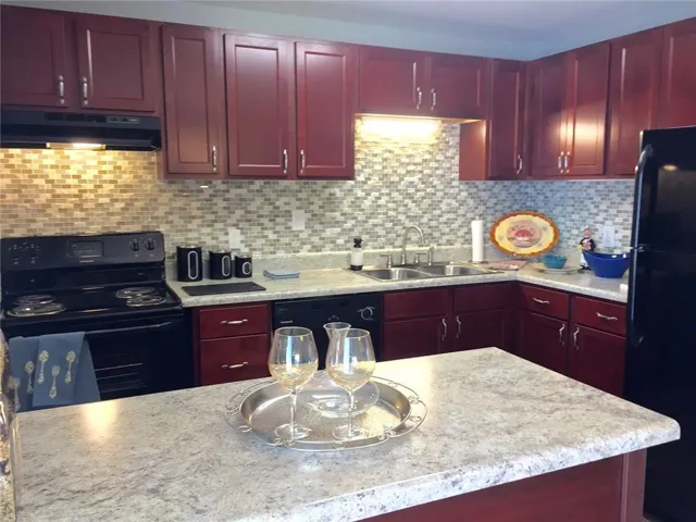 Kitchen with sink, black appliances, and decorative backsplash