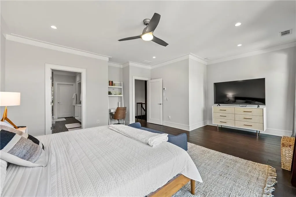 Bedroom featuring dark wood-style floors, recessed lighting, ceiling fan, crown molding, and ensuite bath