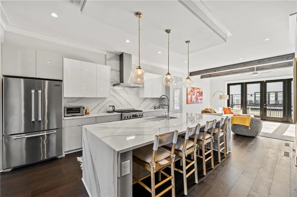 Kitchen with white cabinetry, pendant lighting, a breakfast bar area, high quality fridge, and beamed ceiling