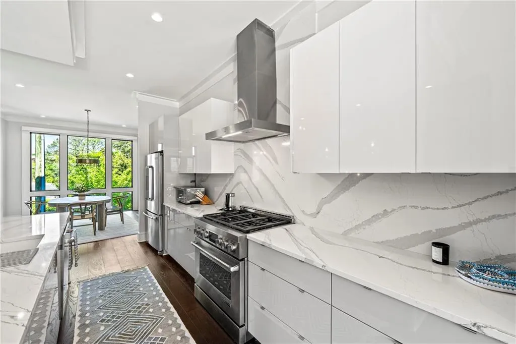 Kitchen with high quality appliances, white cabinetry, light stone counters, modern cabinets, and recessed lighting