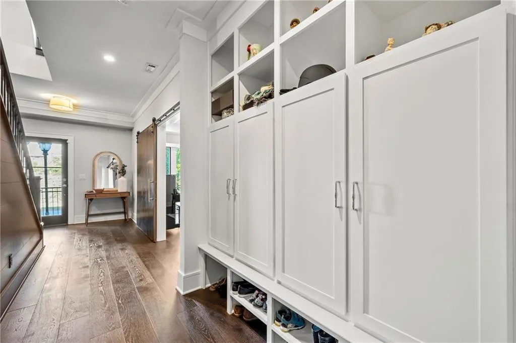Mudroom featuring dark wood-style flooring, a barn door, ornamental molding, and recessed lighting