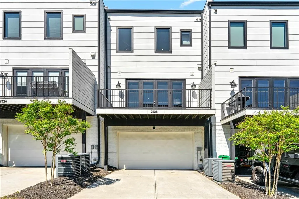 Back of property with concrete driveway, an attached garage, a balcony, and brick siding