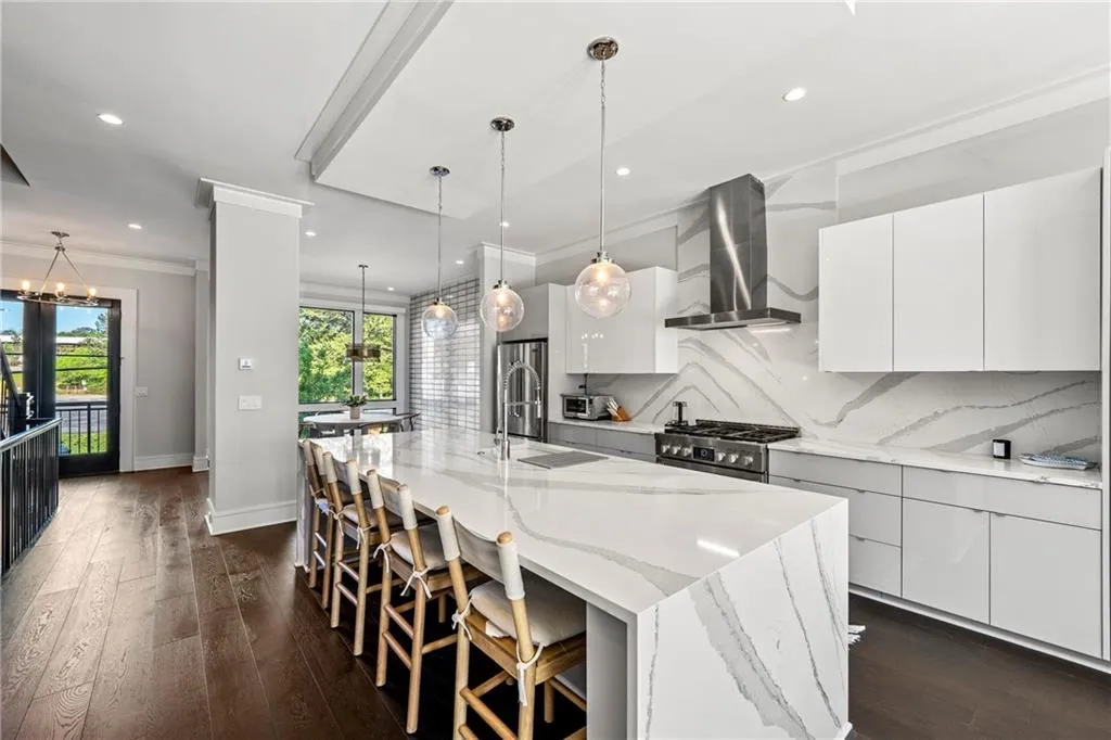 Kitchen with white cabinets, dark wood-type flooring, tasteful backsplash, a breakfast bar, and crown molding