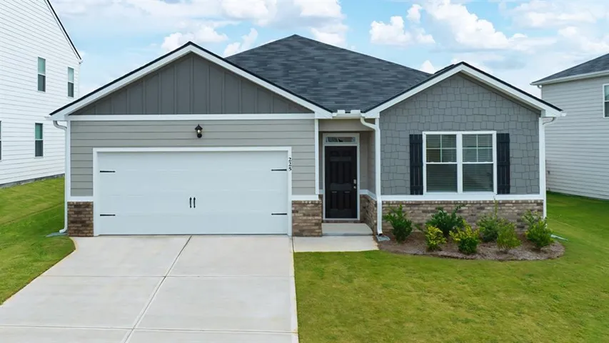 Craftsman house featuring an attached garage, board and batten siding, driveway, and a front yard