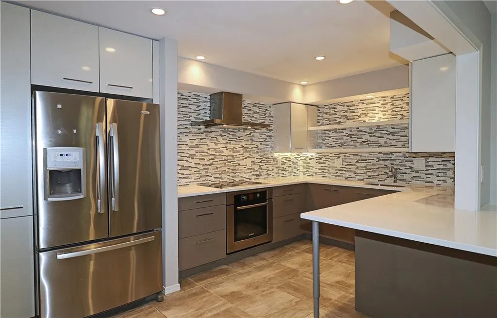 Kitchen featuring stainless steel appliances, wall chimney exhaust hood, backsplash, modern cabinets, and recessed lighting