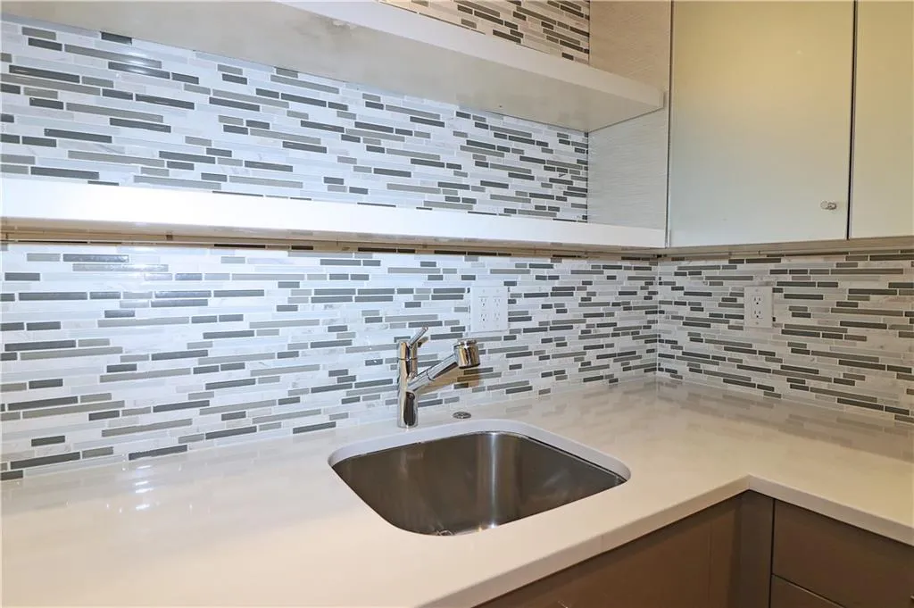 Kitchen featuring decorative backsplash and light stone counters