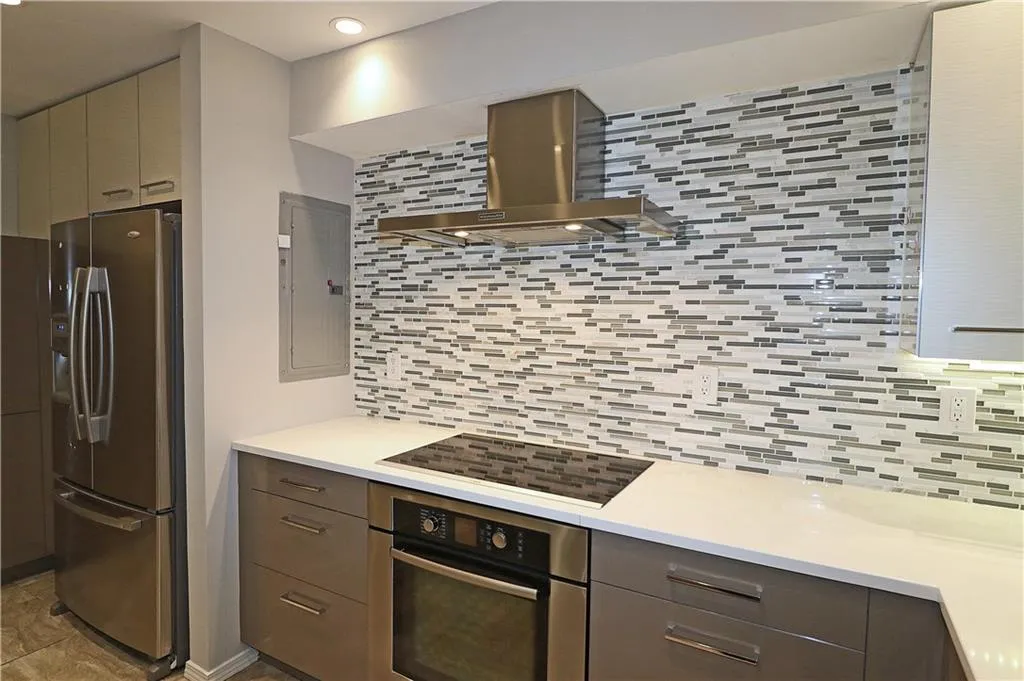 Kitchen featuring appliances with stainless steel finishes, exhaust hood, tasteful backsplash, and electric panel