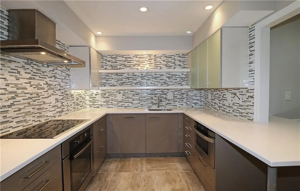 Kitchen featuring wall chimney exhaust hood, stainless steel oven, open shelves, black electric cooktop, and recessed lighting