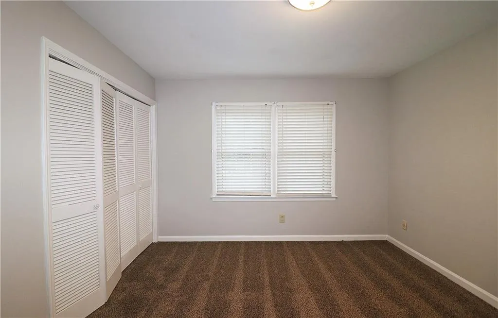 Unfurnished bedroom with dark carpet and a closet