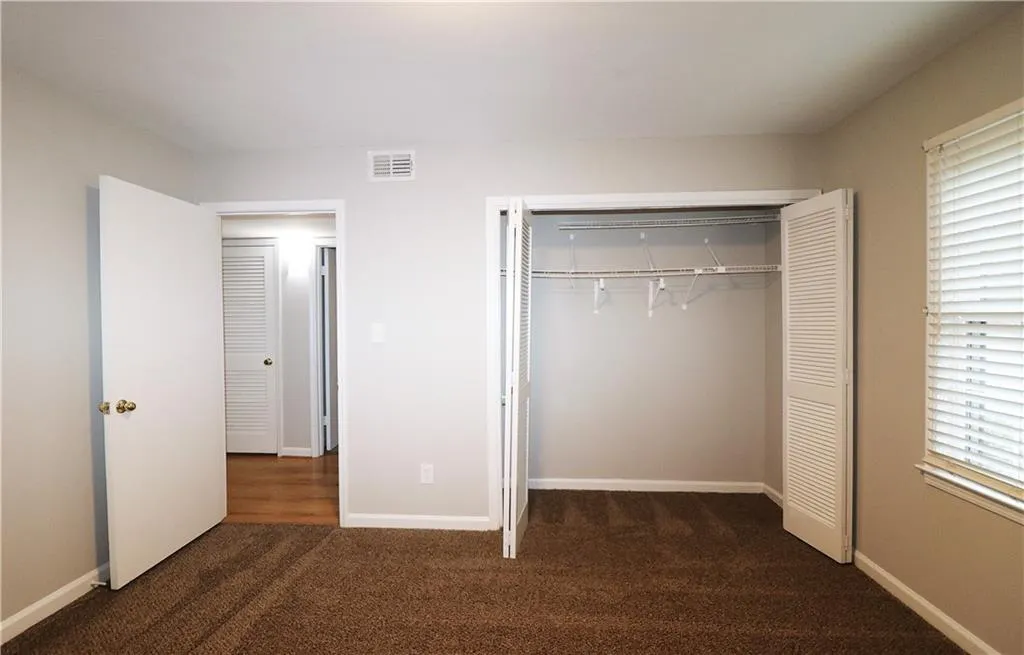 Unfurnished bedroom with dark colored carpet and a closet