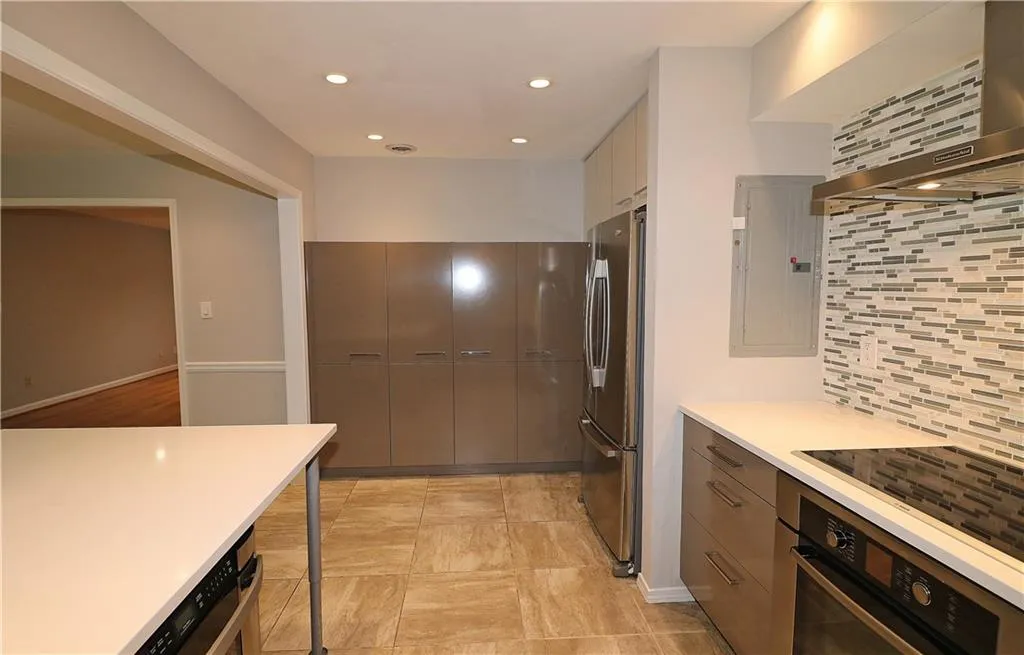 Kitchen with exhaust hood, stainless steel appliances, recessed lighting, tasteful backsplash, and electric panel