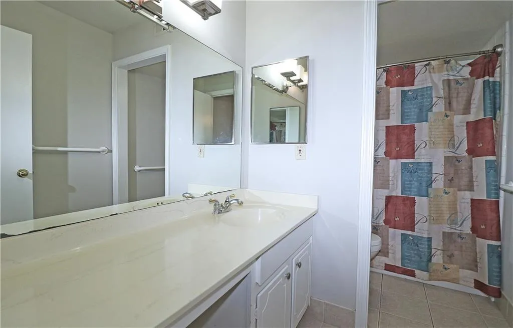 Bathroom with light tile patterned floors, curtained shower, and vanity