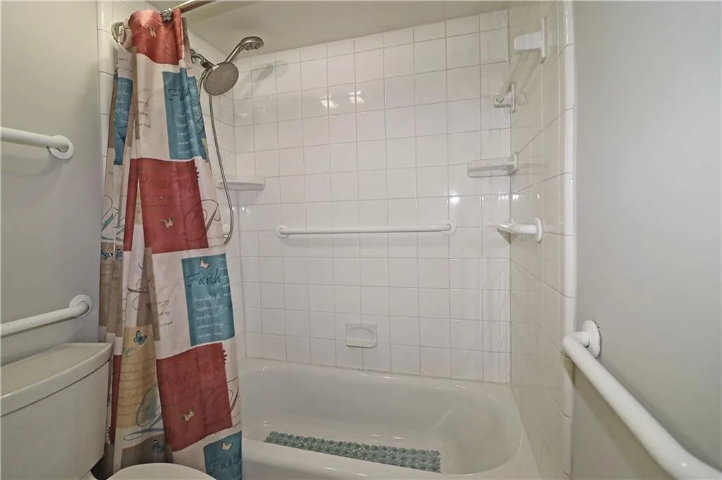 Bathroom with toilet and shower / tub combo with curtain