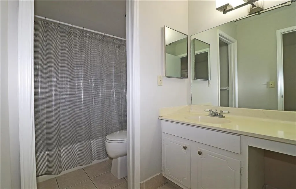 Bathroom with vanity, light tile patterned floors, and a shower with shower curtain