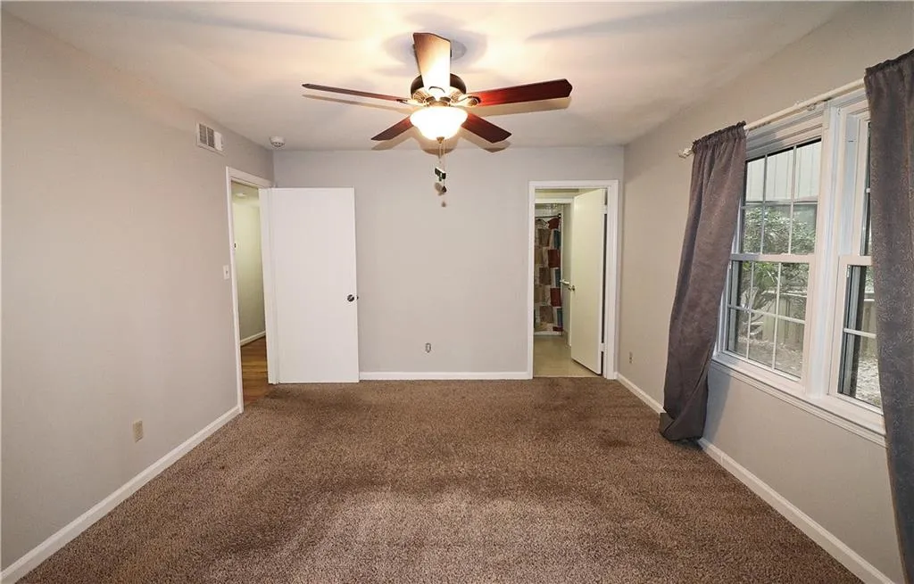 Unfurnished bedroom with carpet, ceiling fan, and ensuite bath