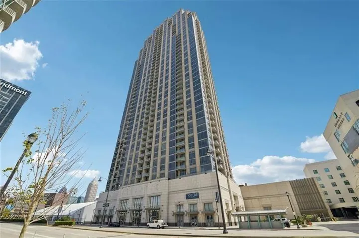 Tall building with a multi-story base, light-colored facade, and numerous windows