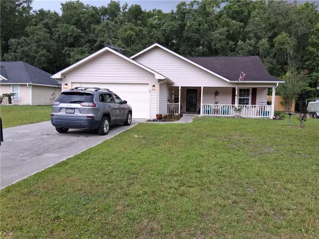 Single-story residence featuring light-colored siding, an attached two-car garage, and a covered front porch with white railings