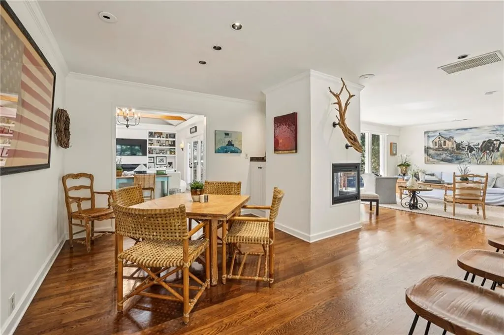 Dining space featuring dark wood-style floors, a chandelier, ornamental molding, a multi sided fireplace, and recessed lighting