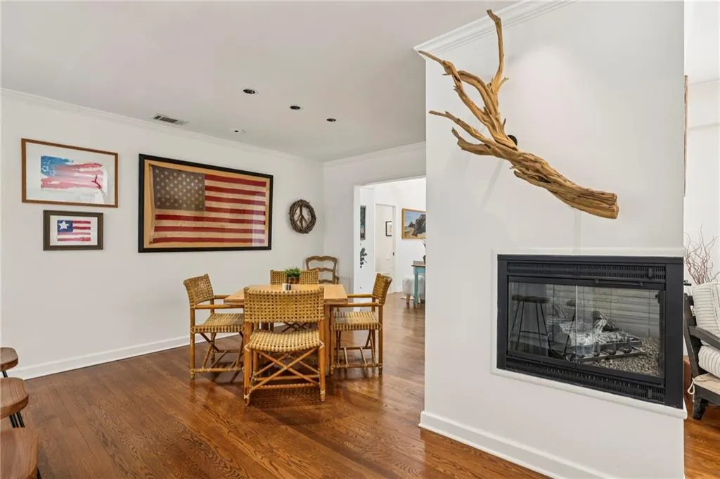 Dining room with ornamental molding, wood finished floors, and a glass covered fireplace