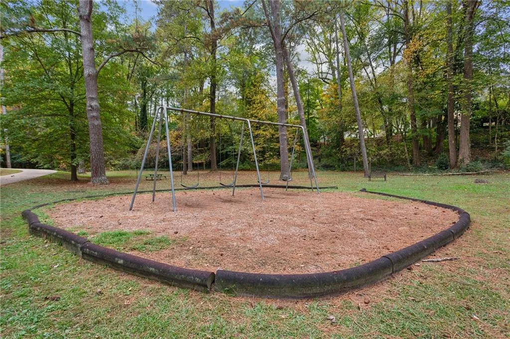 Community jungle gym with view of wooded area and a yard
