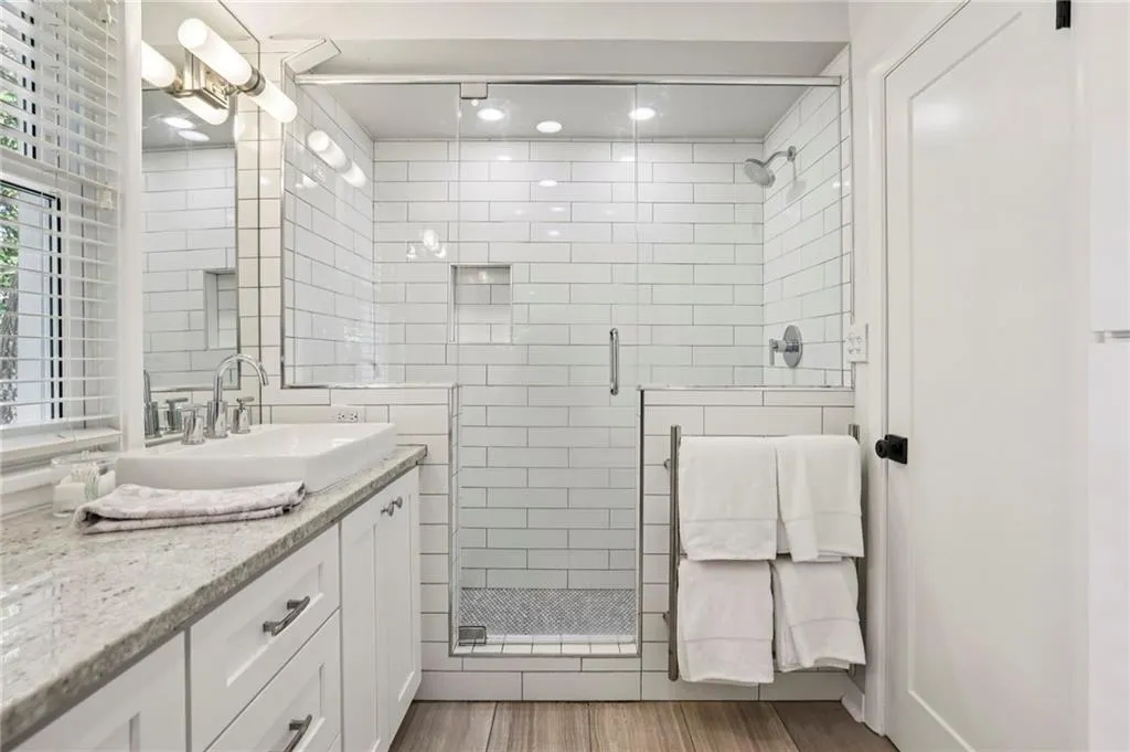 Full bathroom featuring vanity, a stall shower, tile walls, and light wood-type flooring