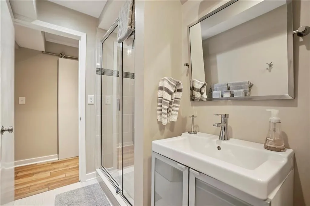 Full bathroom with a stall shower, vanity, and light wood-style flooring
