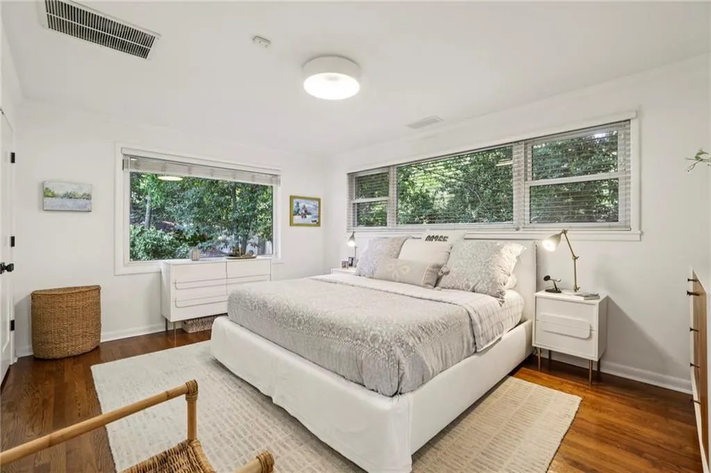 Bedroom with multiple windows, dark wood-style floors, and ornamental molding