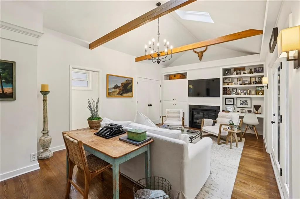 Living area with a glass covered fireplace, dark wood-style flooring, a chandelier, and built in features