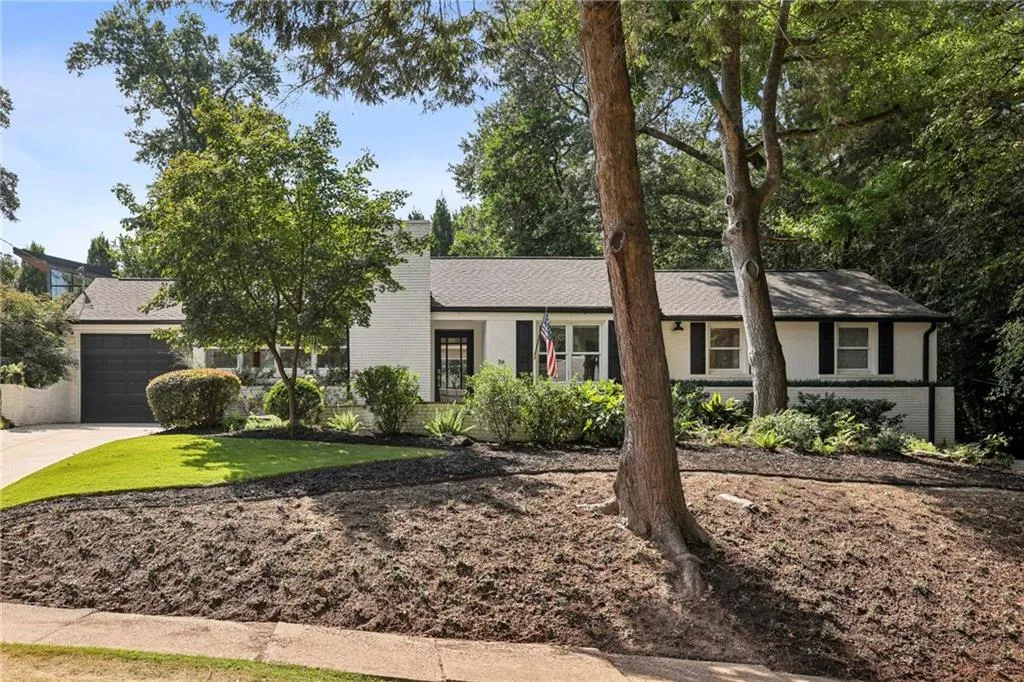 View of front of home with brick siding, driveway, an attached garage, a front yard, and roof with shingles