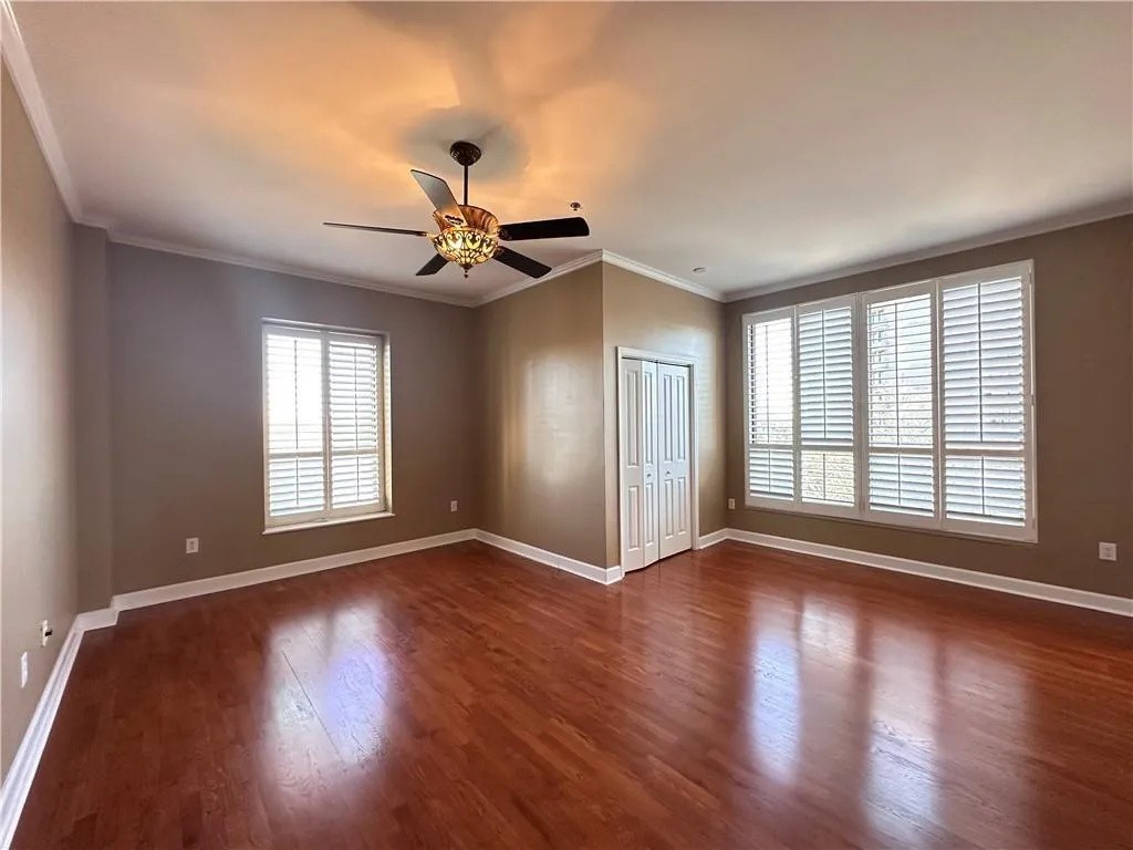 Unfurnished bedroom with dark wood-style floors, a ceiling fan, a closet, and ornamental molding