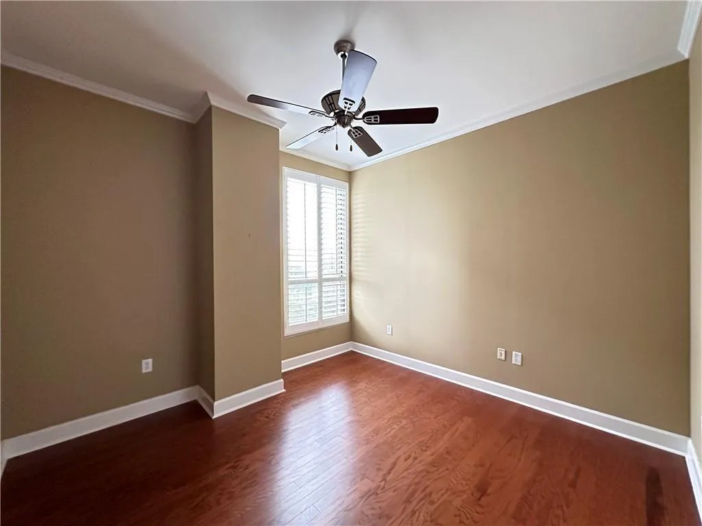 Empty room with ornamental molding, dark wood finished floors, and a ceiling fan
