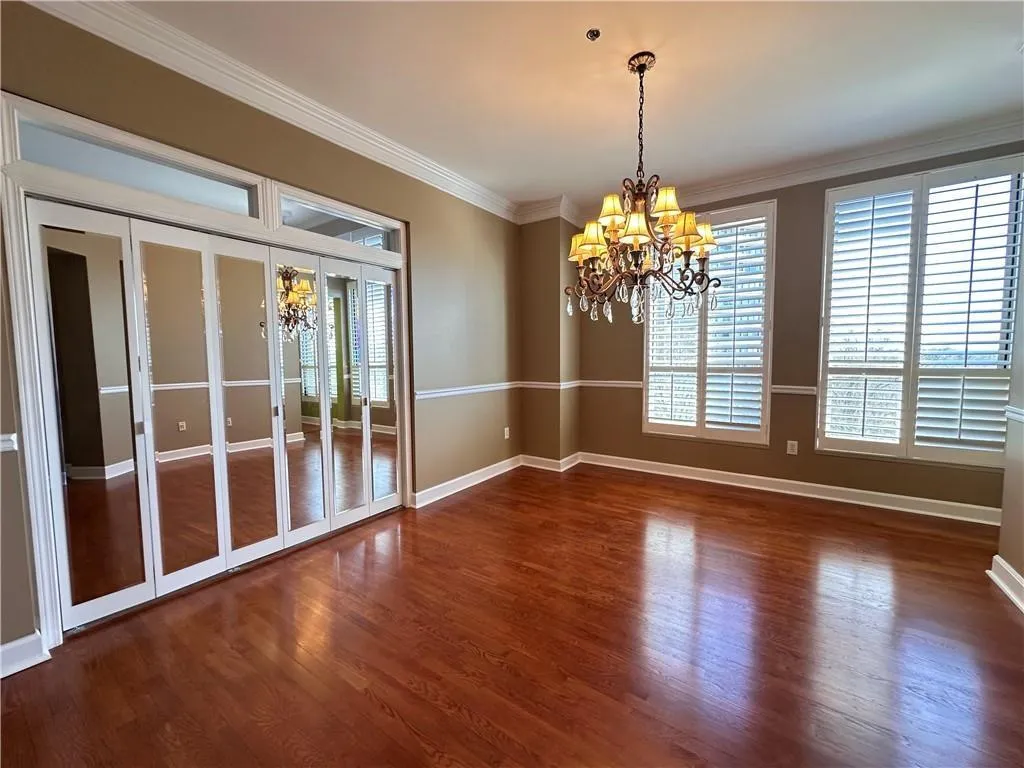 Unfurnished dining area with dark wood-type flooring, hanging lights, and ornamental molding