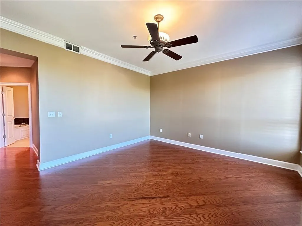 Spare room featuring a ceiling fan, dark wood finished floors, and crown molding