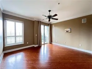 Spare room featuring dark wood-style flooring, ornamental molding, and a ceiling fan