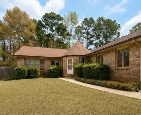 Brick exterior with a unique turret entrance, mature landscaping, and a concrete walkway