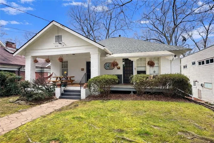 Charming bungalow exterior featuring a white brick facade and a covered front porch